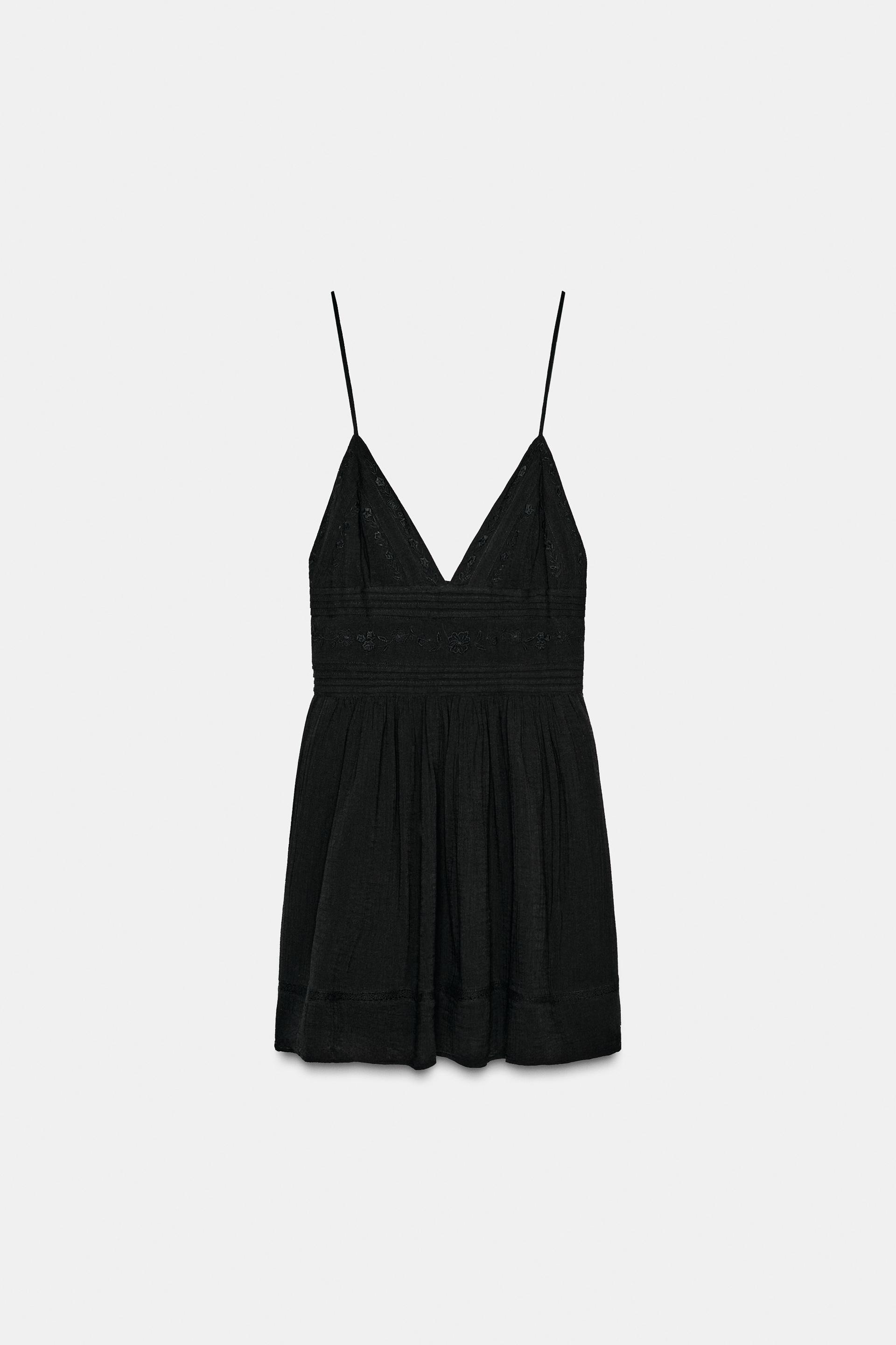 Front view of a short black dress with a V-neckline and thin straps. Tonal embroidery detail on the chest.
