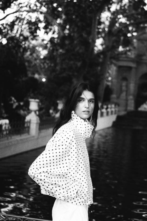 Sada bílé prošívané bundy s černými puntíky, stojáčkem a dlouhými rukávy.