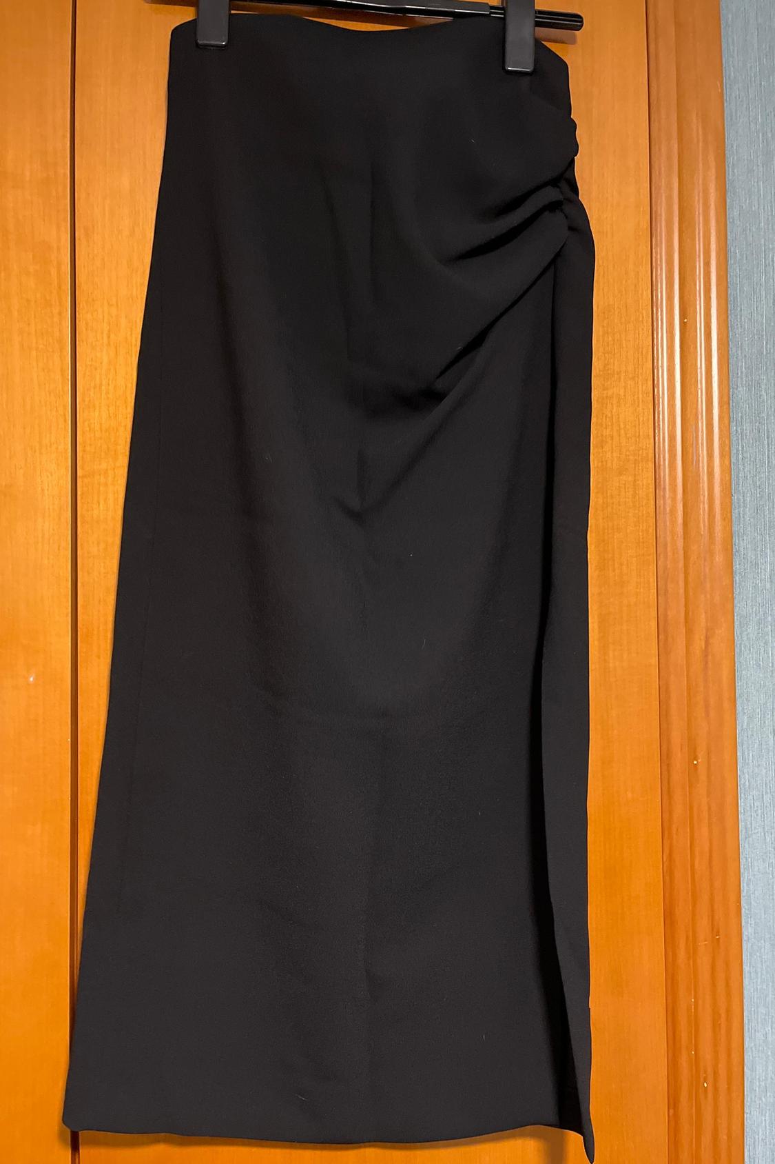 Front view of black skirt with side pleat and knee-length.