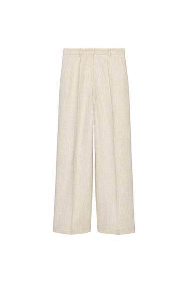 Front view of beige trousers with pleats and side pockets.