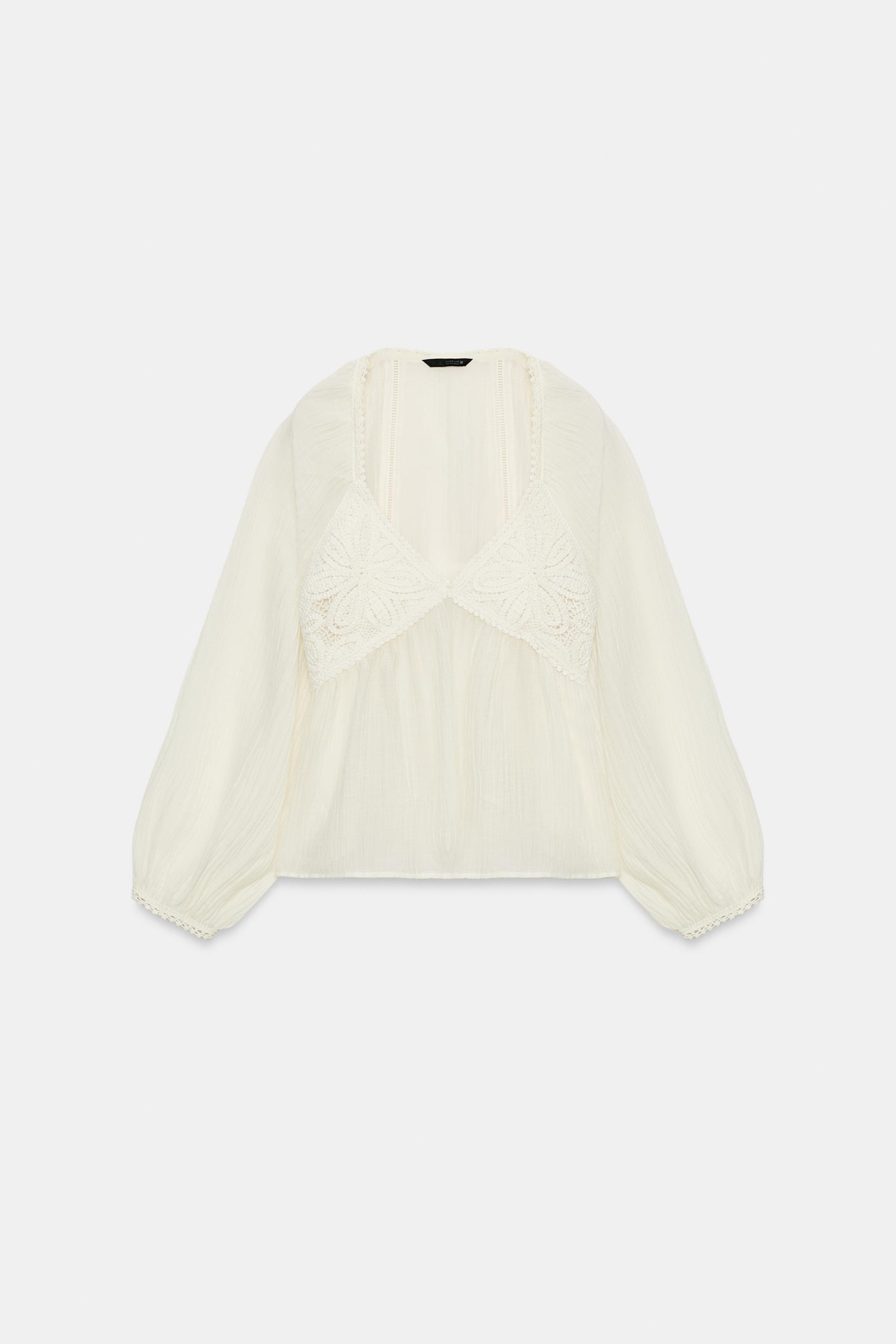 Front view of a raw blouse with a V-neck, long puffed sleeves, and crochet detail on the chest.