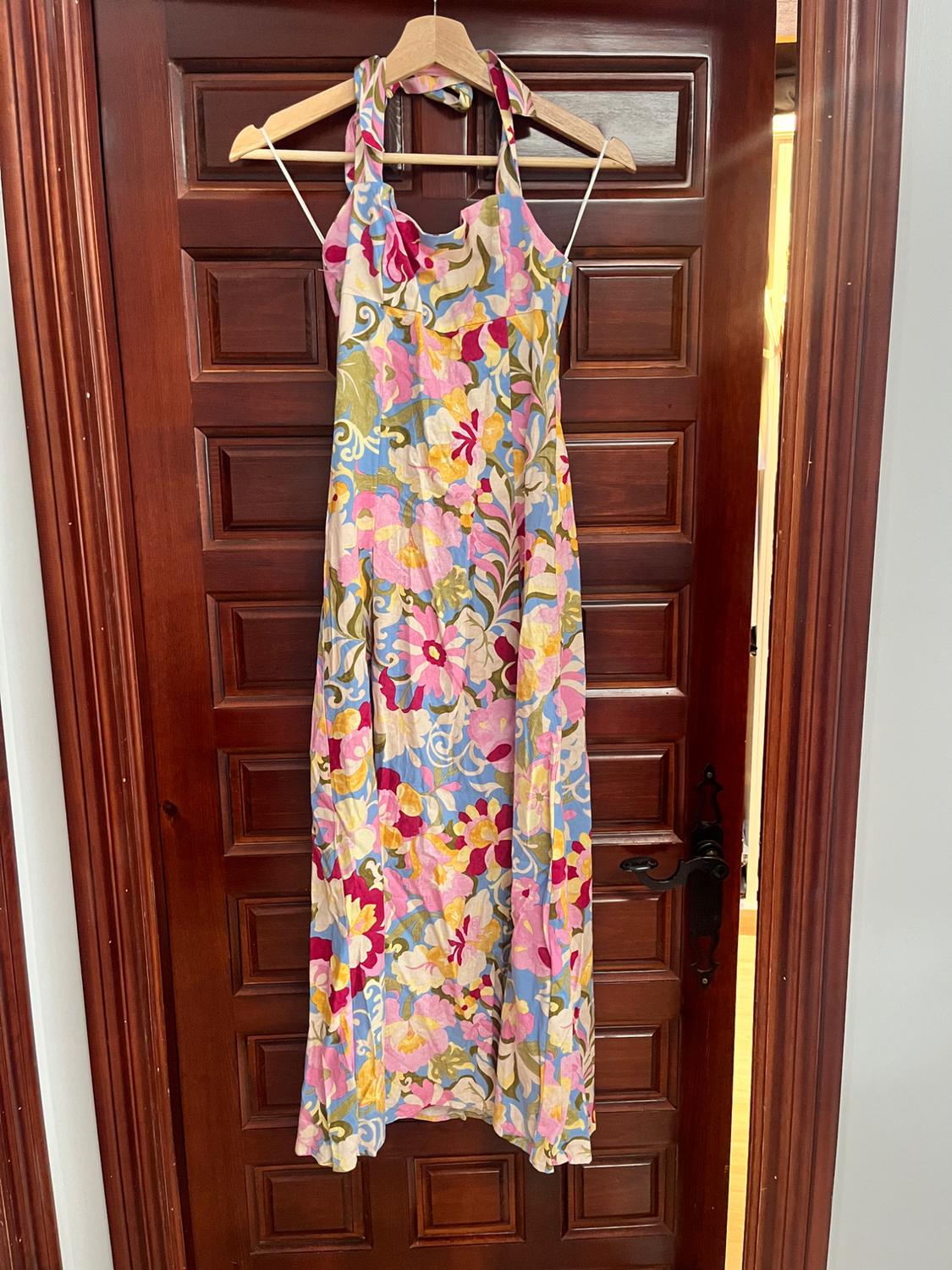 Long dress with a colourful floral print hanging on a dark wooden door.
