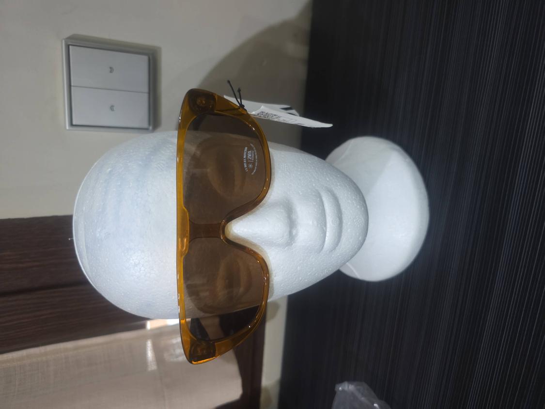 White mannequin head wearing large, translucent brown sunglasses. They have a sticker on the lens with the text ZARA.