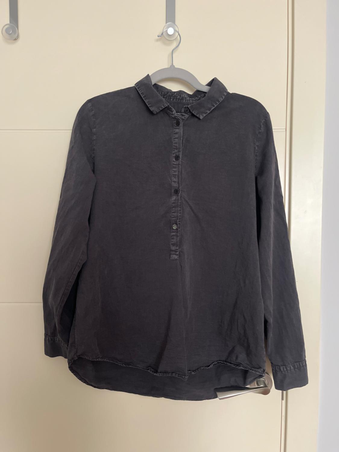 Front view of a black shirt with a classic collar and partial button fastening.