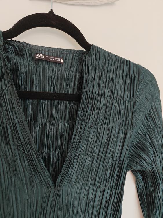 Dark green pleated dress hanging on a black hanger. Visible label: "ZARA, EUR MEX 28, MADE IN TURKEY".