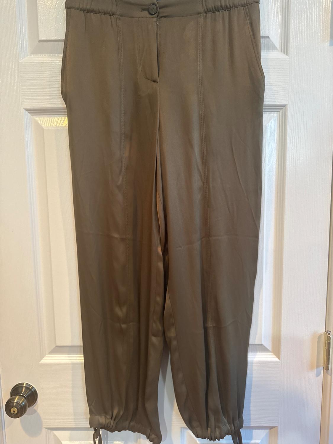 Brown trousers hanging on a white door, with an elasticated waist and drawstring ankles.