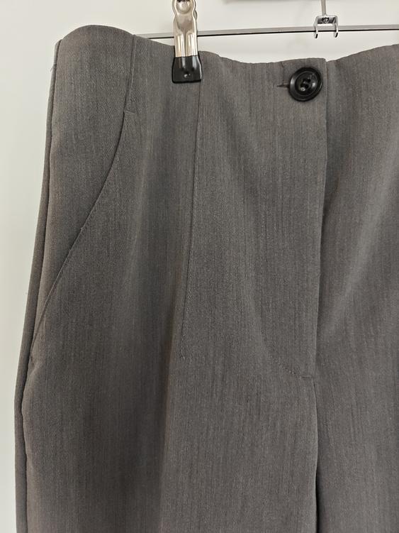 Grey plain fabric trousers hanging on a hanger, with a visible black button at the top. White background.