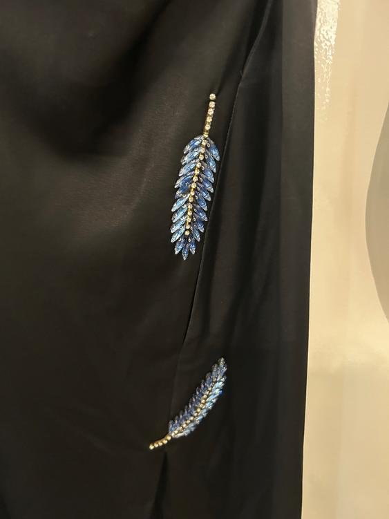 Black fabric with shiny blue and gold leaf details. Light background.