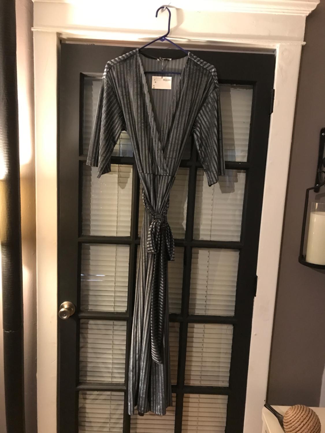 Front view of a long dress with vertical stripes and a belt, V-neck and three-quarter sleeves.