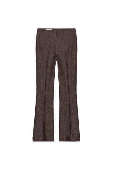 Front view of high-waisted brown pants with front seam, contrasting topstitching, and flared hem. Front zip fastening.
