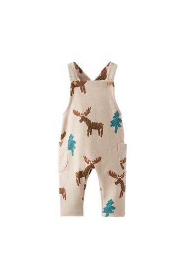 Ribbed beige children's dungarees with moose and pine tree print. Casual design with buttoned straps and side pockets on a white background.