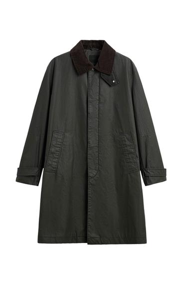 Long dark green coat with a brown corduroy collar, concealed front fastening and side pockets on a white background.