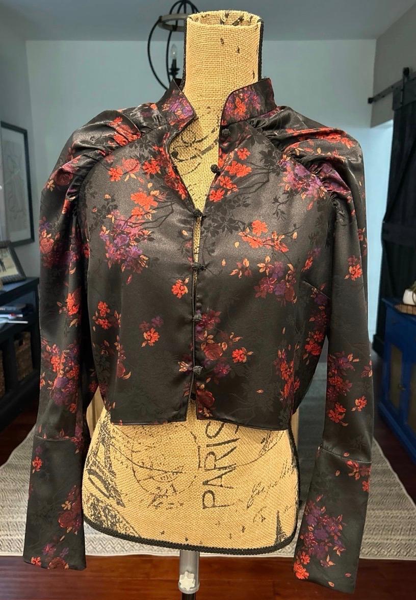 Black blouse with a floral print and puff sleeves on a mannequin with the word PARIS in a room.