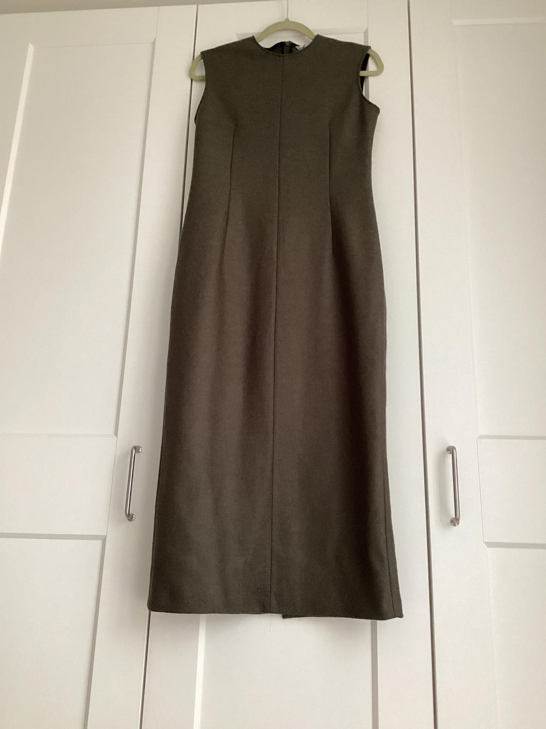 Brown sleeveless dress hanging on a hanger in front of a white wardrobe with panelled doors.
