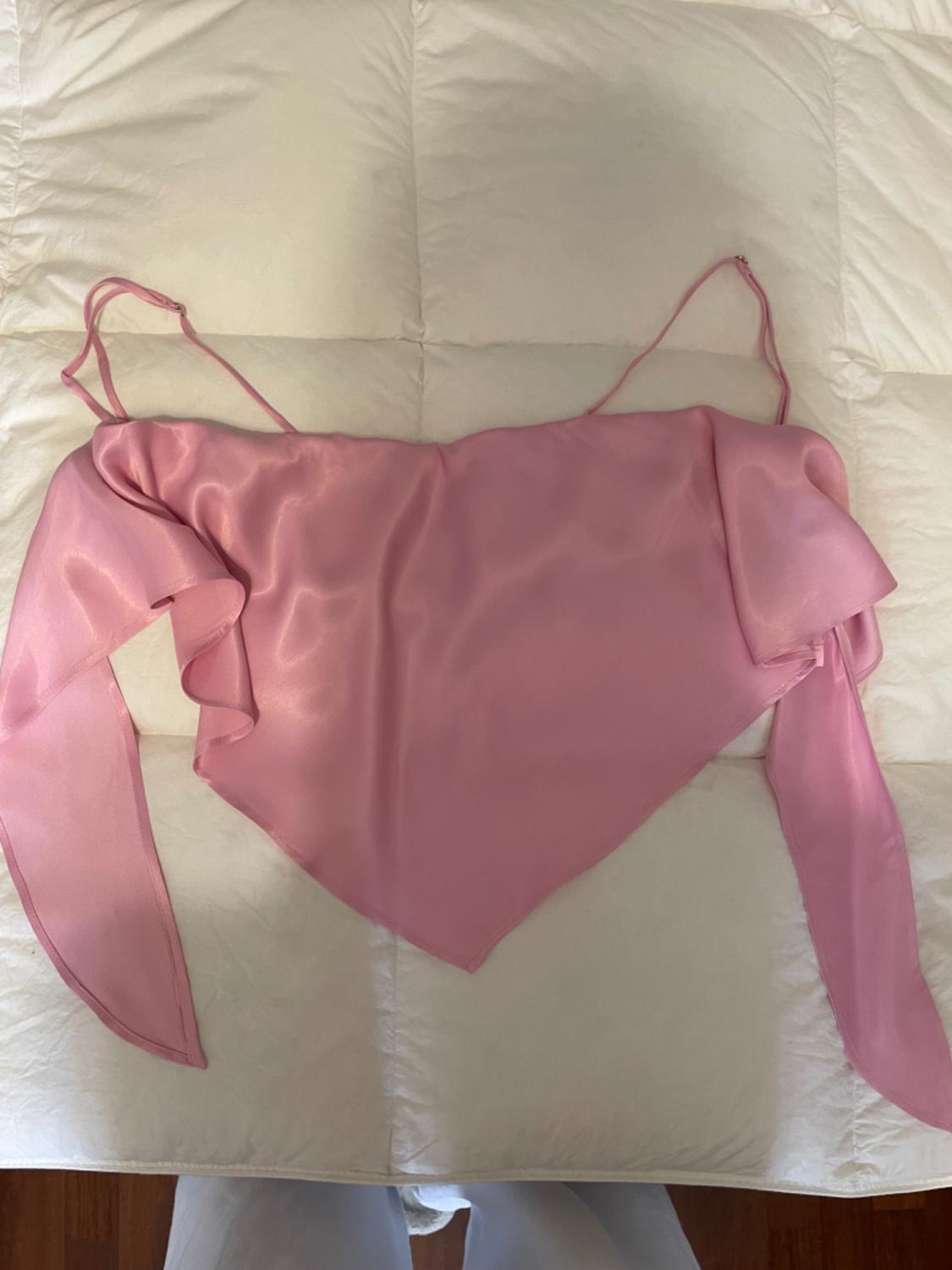 Satin pink camisole top with an asymmetrical design on a quilted white bedspread.