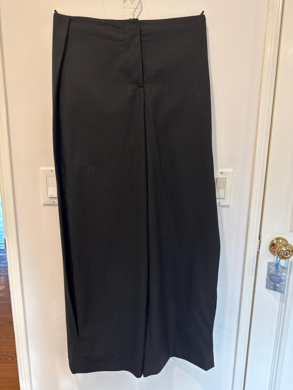 Black dress trousers hanging on a hanger over a white door. Fabric with fine vertical stripes.