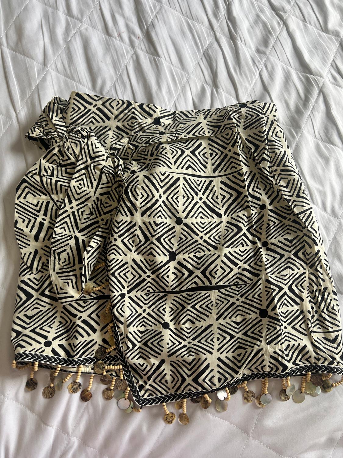 Black and white geometric print skirt, embellished with beads and discs on the hem, on a white quilted bedspread.