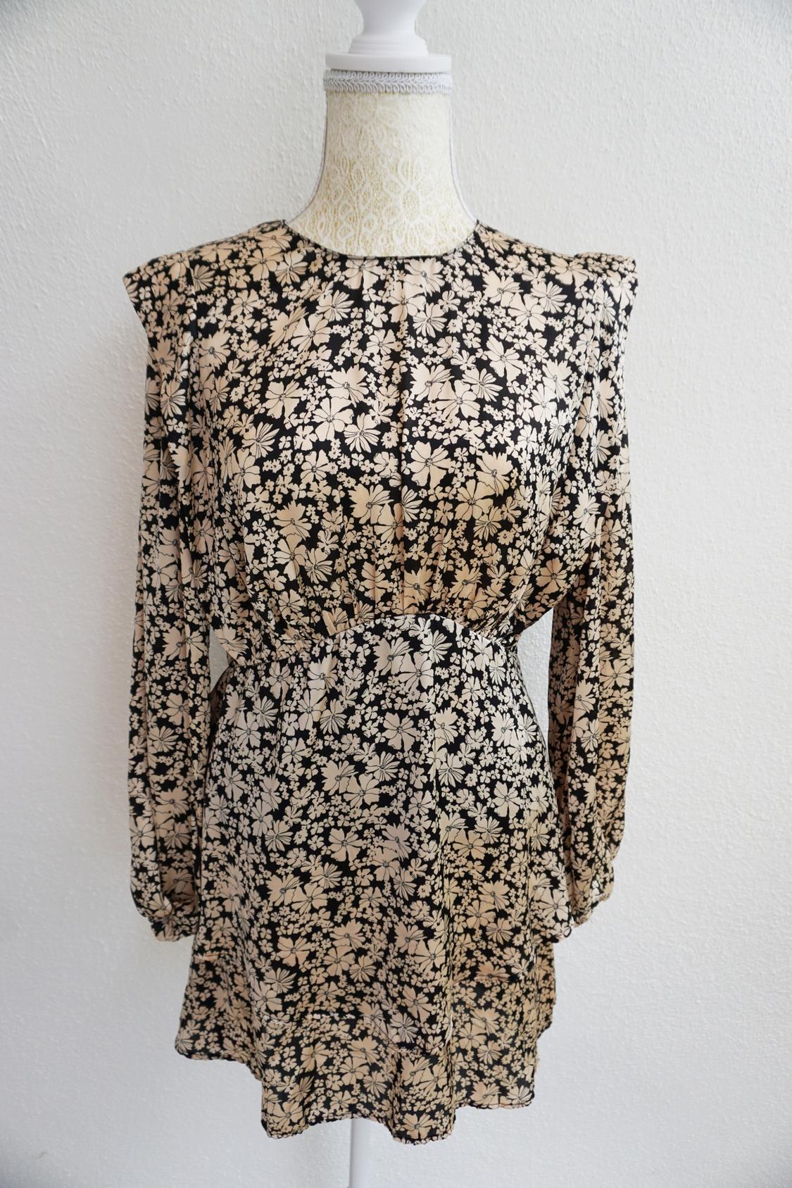 Long-sleeved dress with a floral print in beige and black tones on a white mannequin, white background.