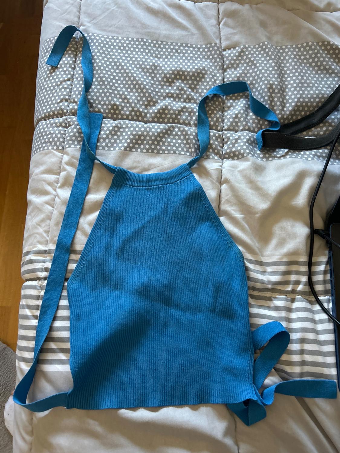 Sleeveless blue top with straps on a grey and white polka dot and striped quilt.