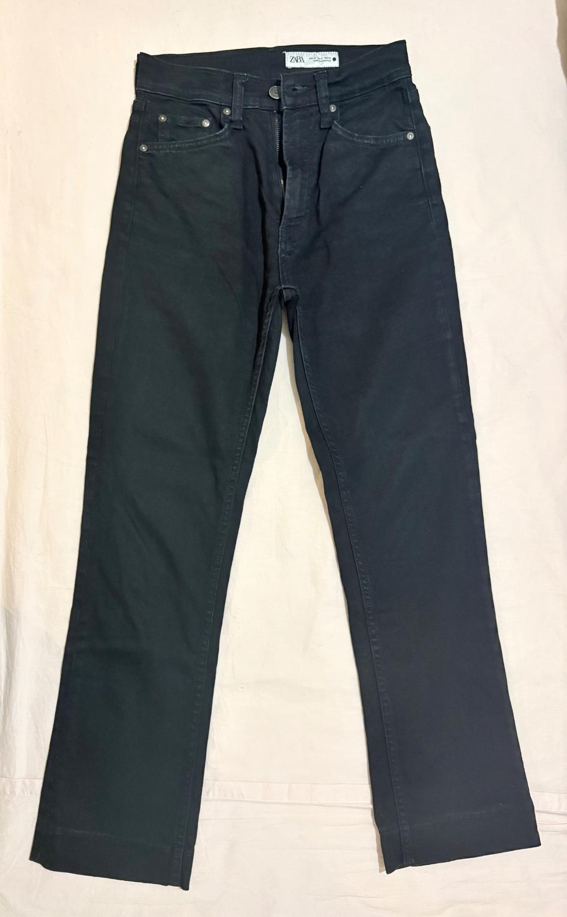 Dark denim jeans laid out on a light fabric background. The inside label reads ZARA.