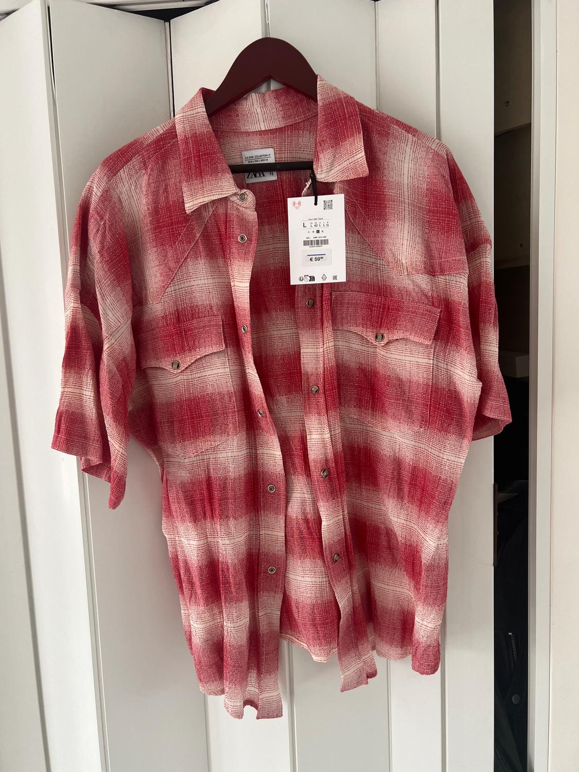 Red and white checked shirt hanging on a brown hanger, with a €69 price tag visible in the centre.