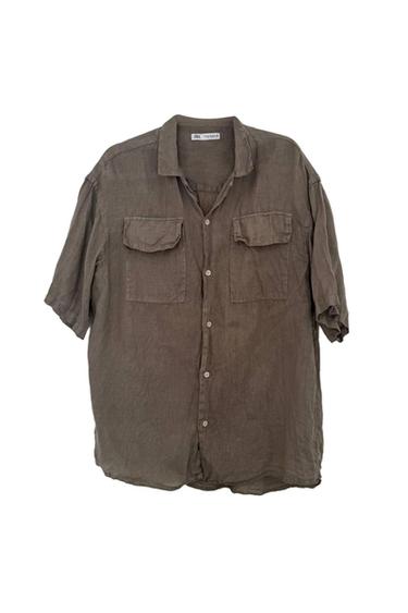 Brown short-sleeved shirt with a collar, button fastening and two chest pockets with flaps. Label with ZARA text. White background.