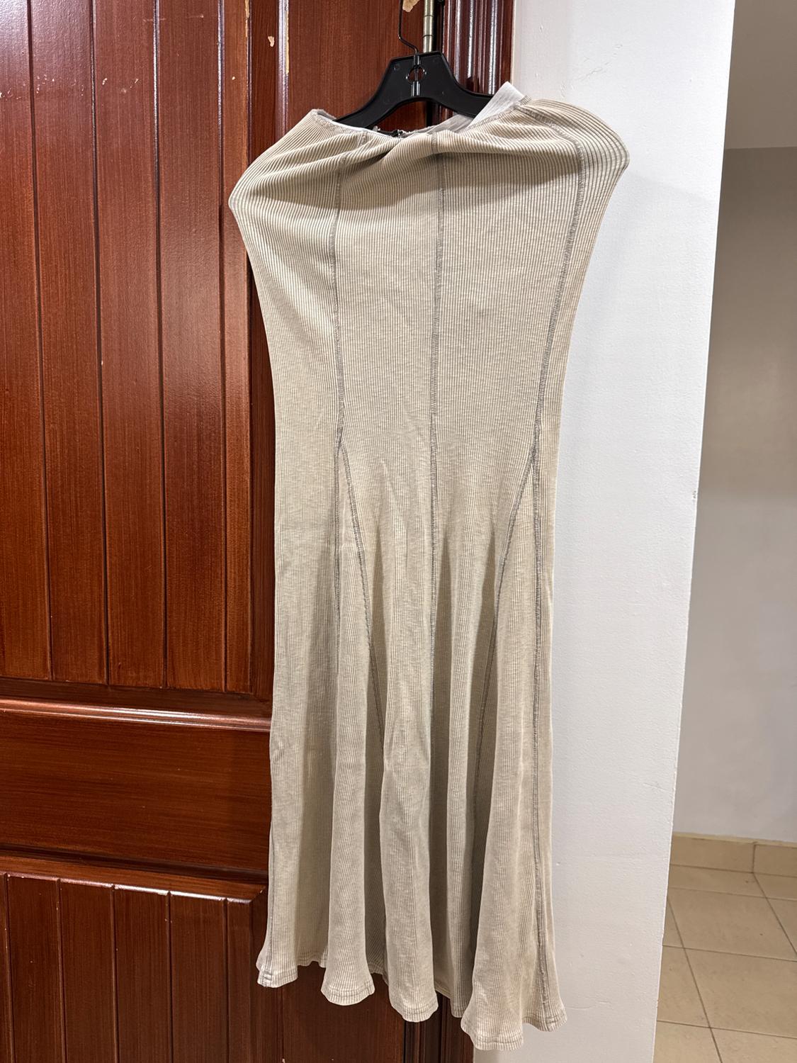 Beige ribbed dress hanging on a black hanger over a brown wooden door. Indoor environment.