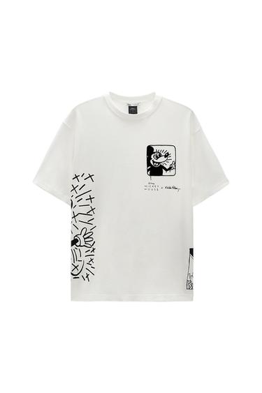 Λευκό T-shirt με μαύρη γραφική στάμπα ενός κινούμενου σχεδίου χαρακτήρα και κείμενο "Disney Mickey Mouse x Keith Haring" στο στήθος.