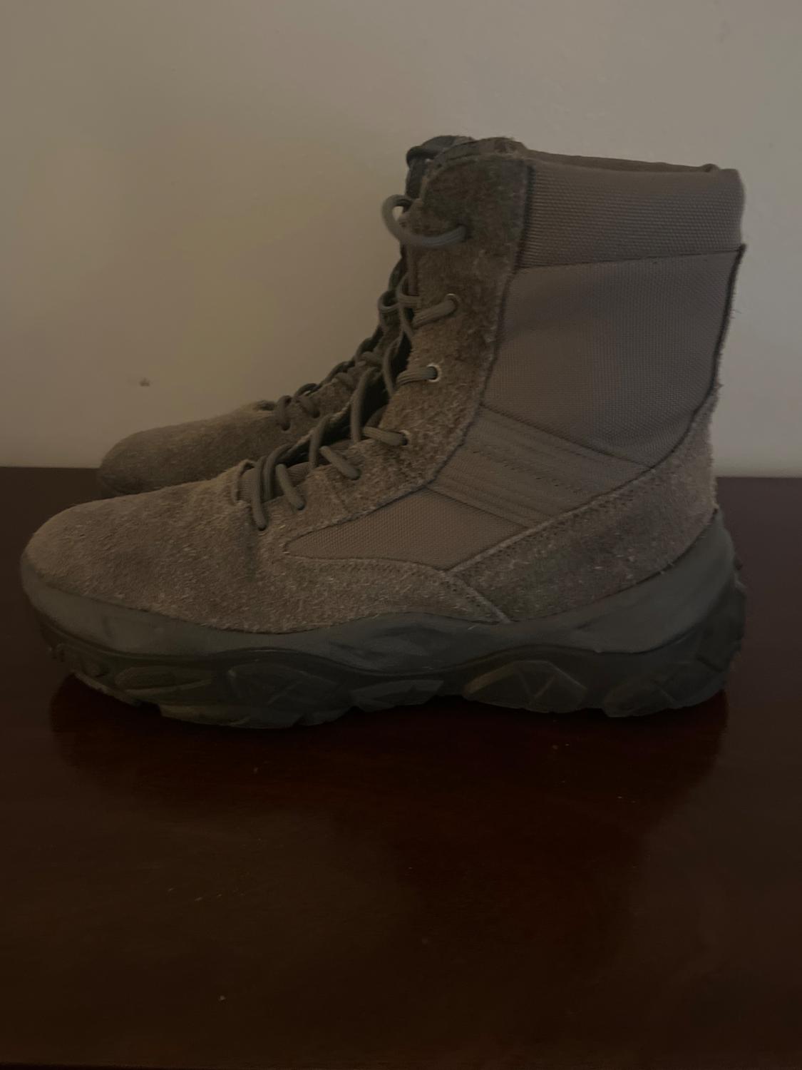 Brown hiking boots with a thick sole and laces, on a dark wooden surface.
