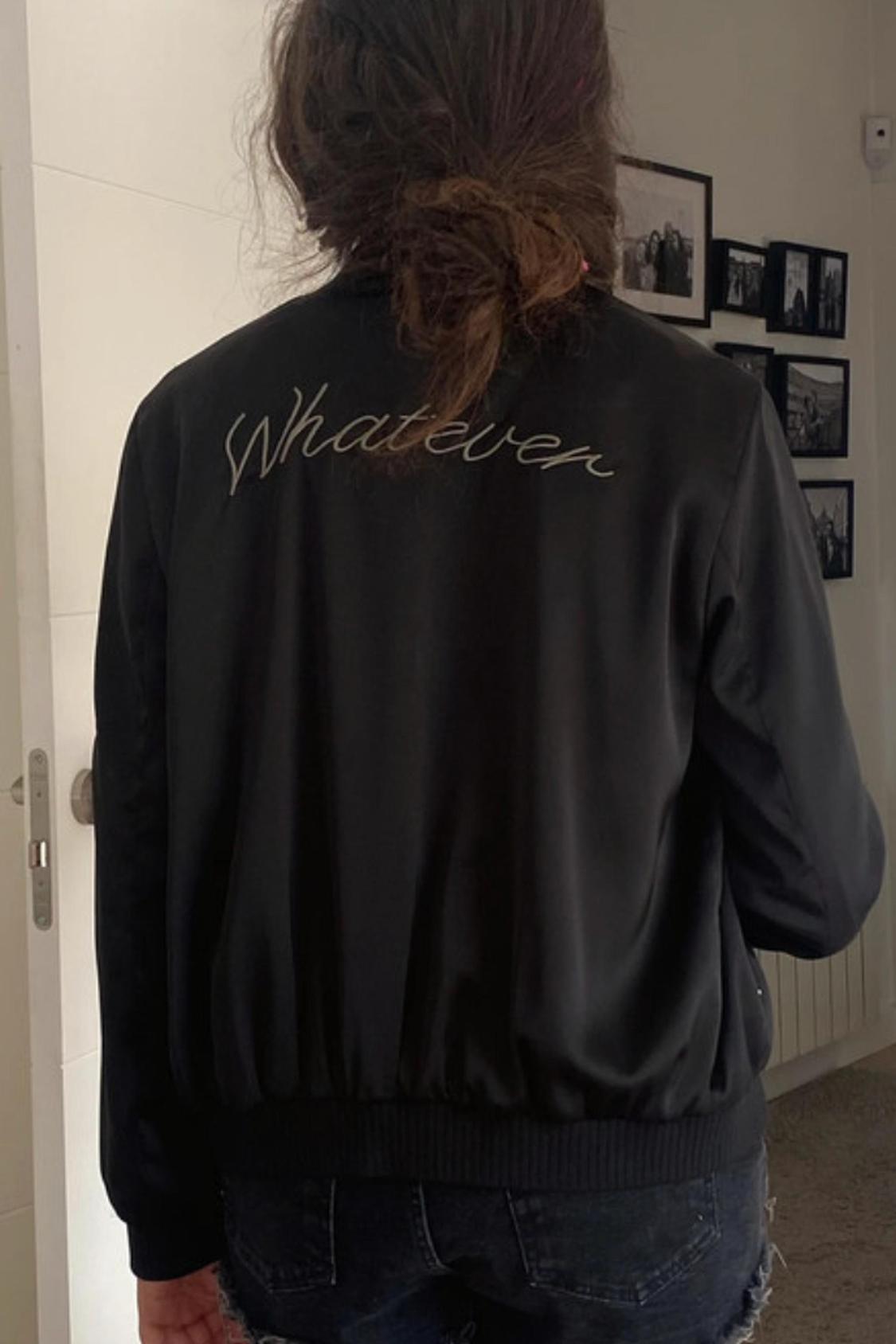 Rear view of black jacket with text 'Whatever' on the back.