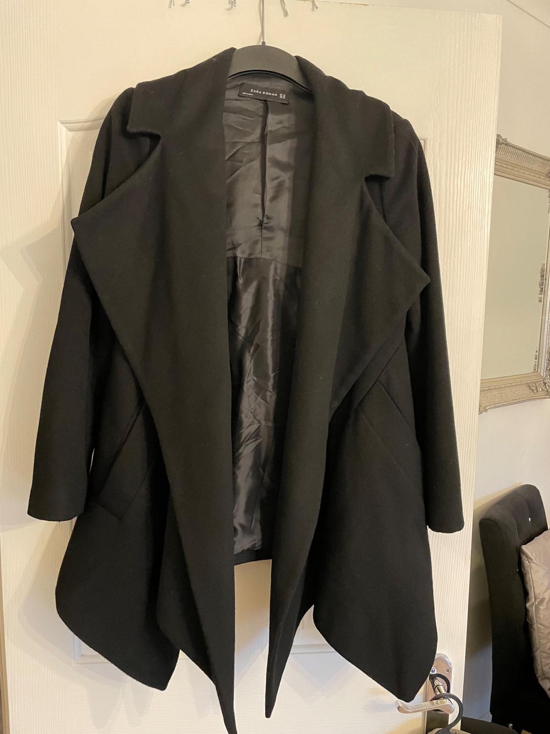 Front view of black coat with wide lapels and side pockets.