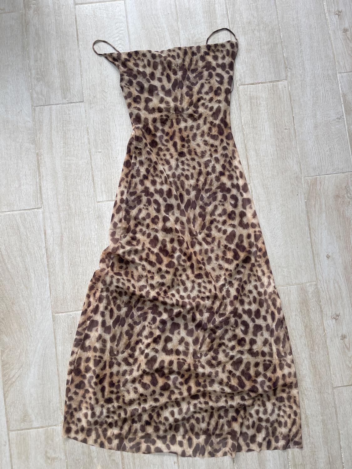 Long, spaghetti strap dress with a leopard print in brown and black tones, on a light wood floor.