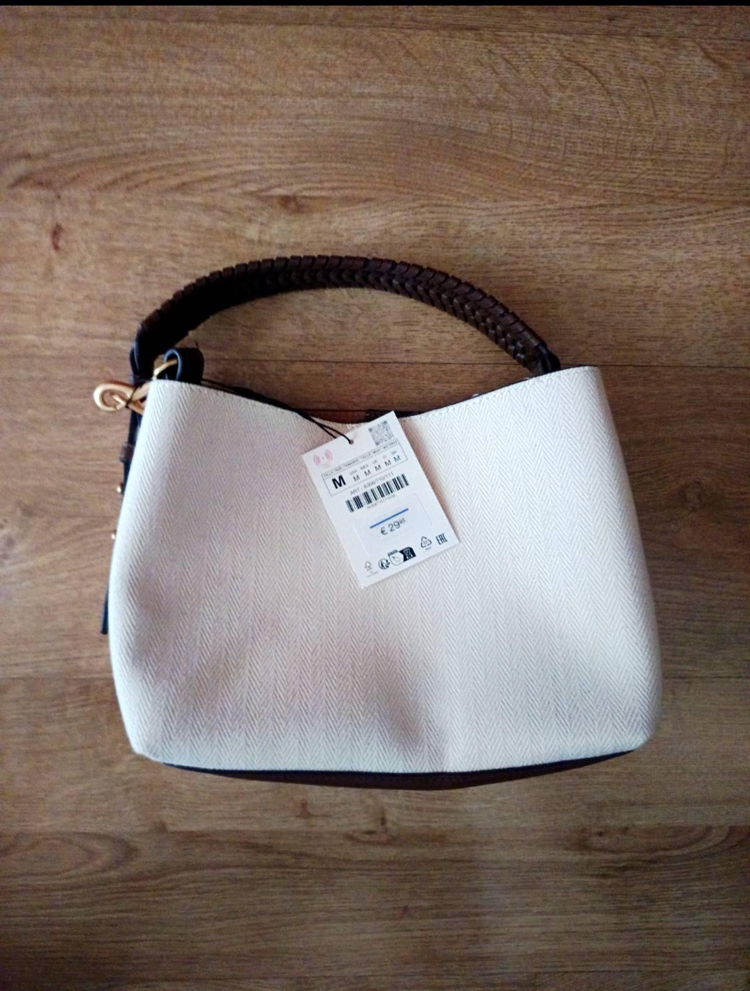 Light-coloured bag with a herringbone pattern and braided brown handle on a wooden floor. Text: M M M M M £29.95 EAC.