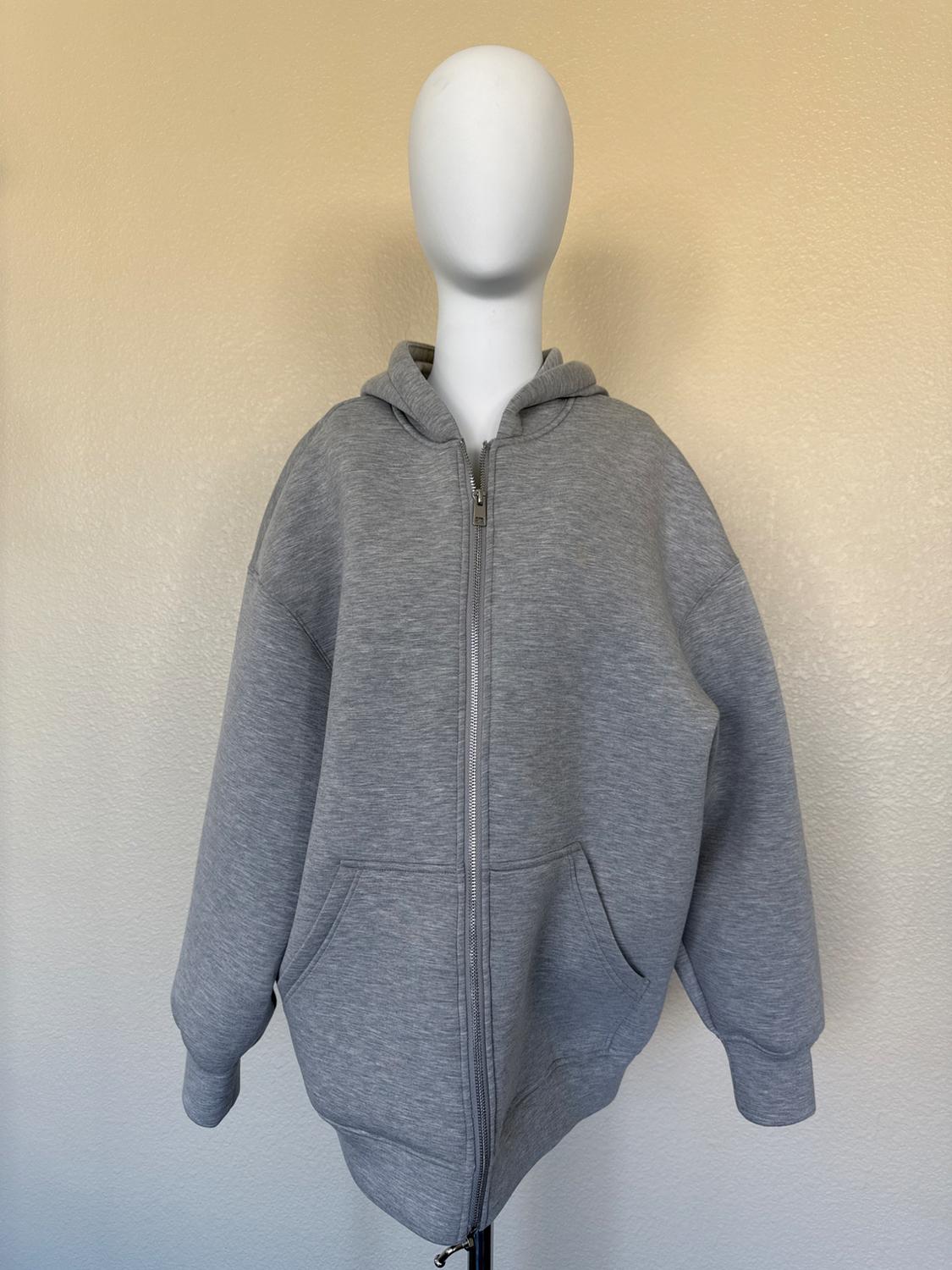 Mannequin in a gray hooded sweatshirt with a front zipper, on a beige background.