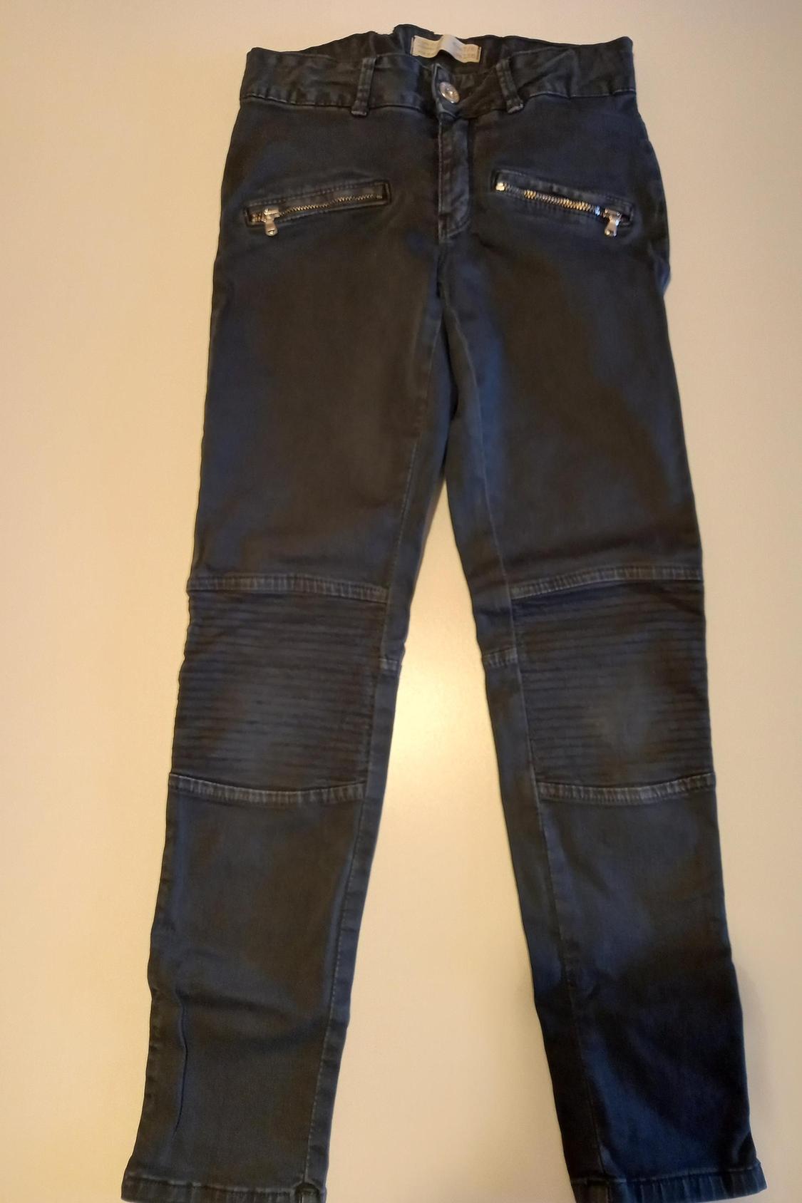 Front view of dark trousers with zips on the front pockets and ribbed knee panels.