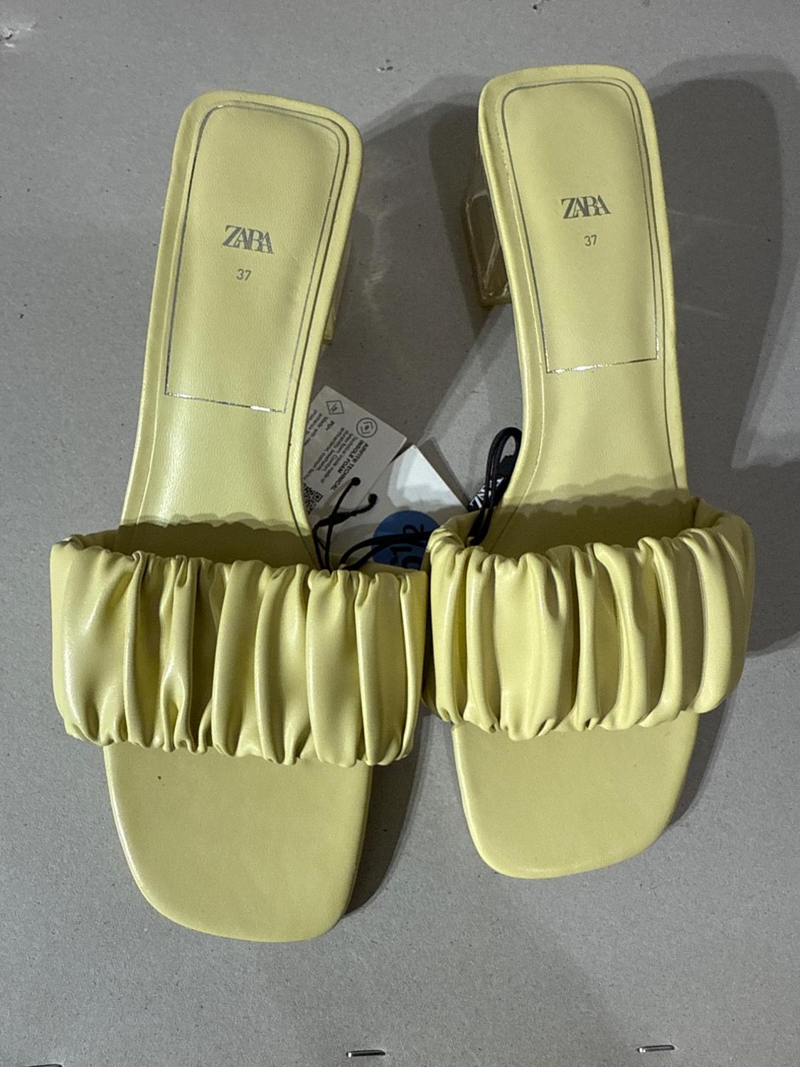 Yellow sandals with transparent heel and gathered detail on the upper. Visible text: "ZARA 37". Hanging tag present.