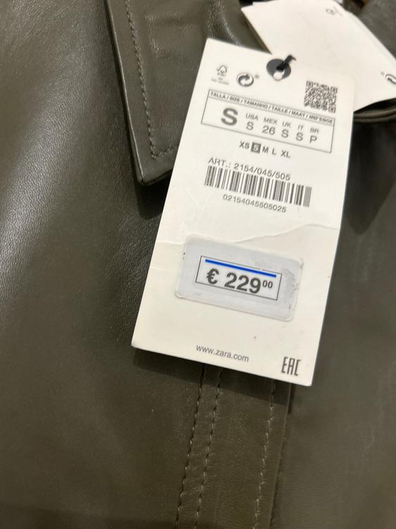Price tag of 229 euros on a brown leather garment. Size S. Visible text: www.zara.com, EAC. Barcode present.