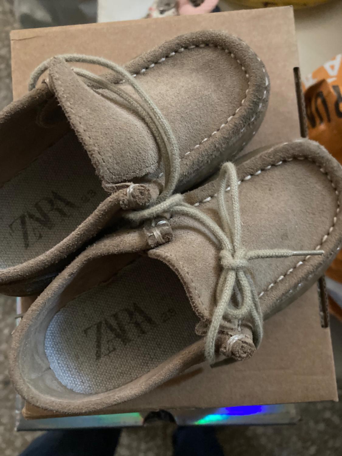 Brown children's shoes with laces on a cardboard box, 'ZARA' text visible on insole.