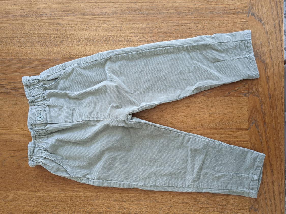 Light gray boys' pants with elastic waist and button, on a wooden table.