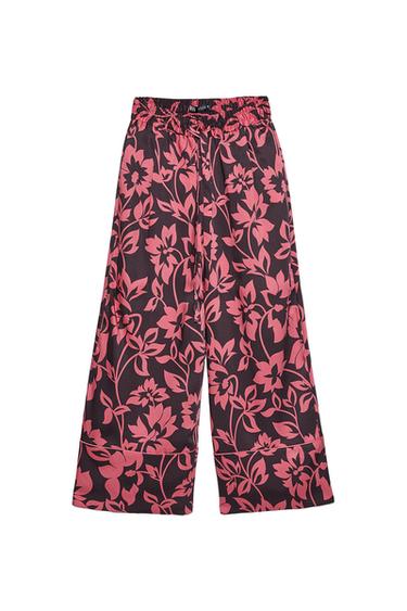 Dark wide-leg trousers with a pink floral print. Elasticated waistband with a drawstring and ZARA label. Piped trim detail at the hem. White background.