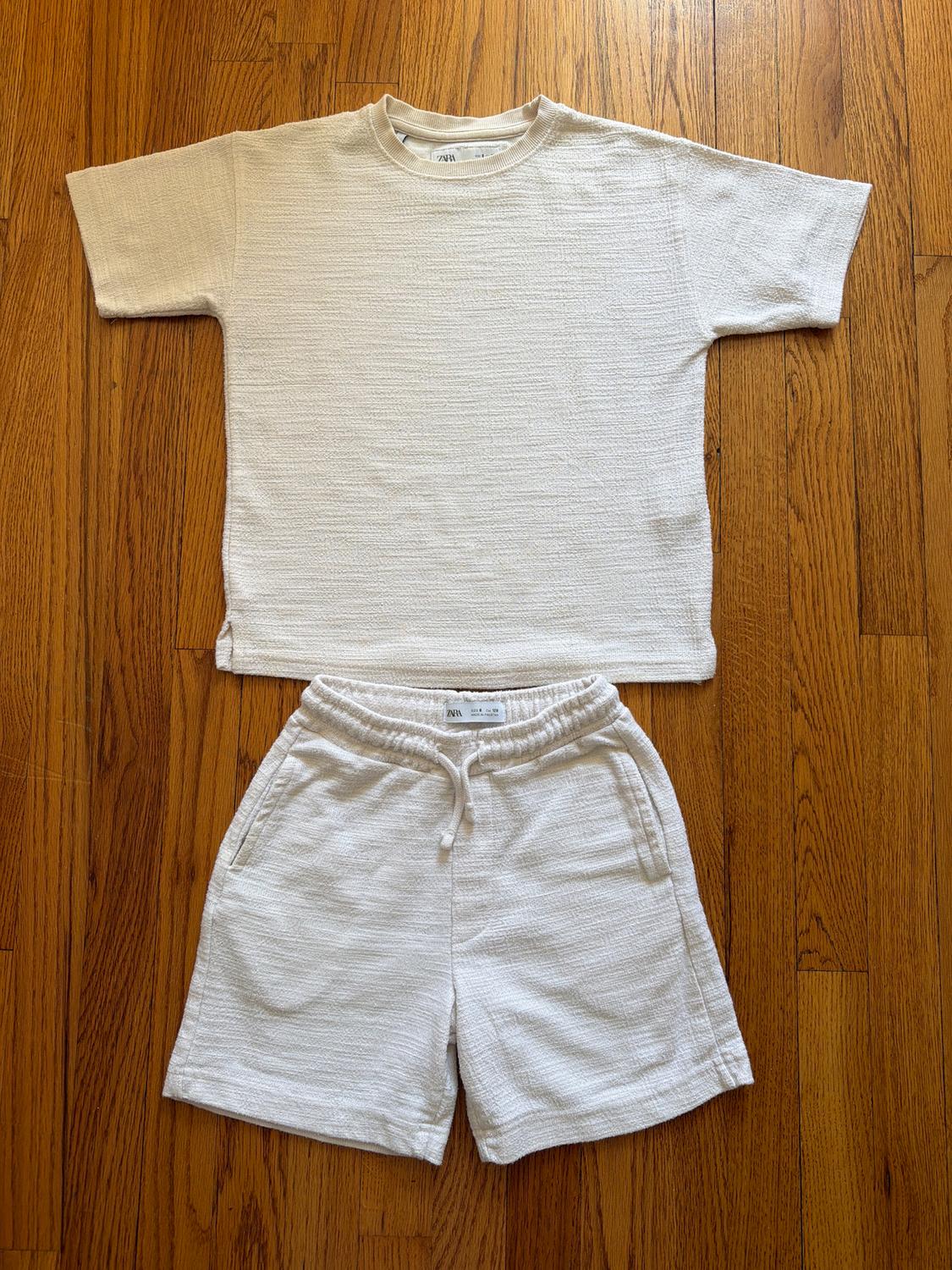 White textured fabric t-shirt and shorts set on a wooden floor. Label visible on the waistband of the shorts.
