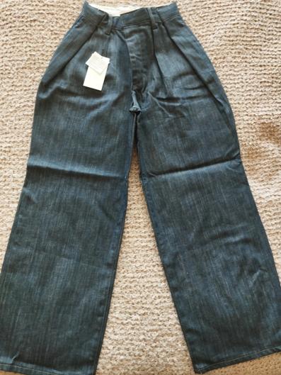 Dark blue, wide-leg denim jeans with a white label, placed on a beige rug.