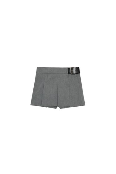Front view of grey pleated shorts with black belt and metal buckle.