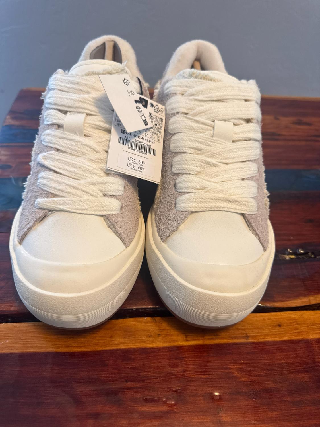 White and grey lace-up trainers on wood. Text: ART: 2226/520/202 12226520202396 US $ 69.90 UK £ 49.99