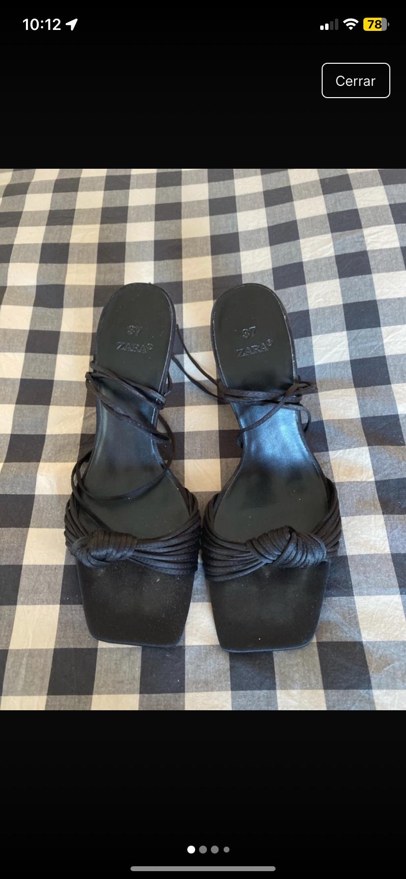 Front view of black sandals with knotted straps and a square toe, size 37, on a checked background.