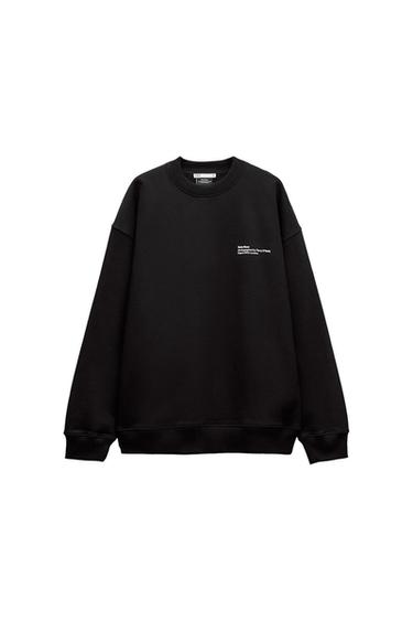 Black sweatshirt with white text on the chest that reads: "Kate Moss, Photographed by Terry O'Neill, Reissued by Iconic Images". White background.