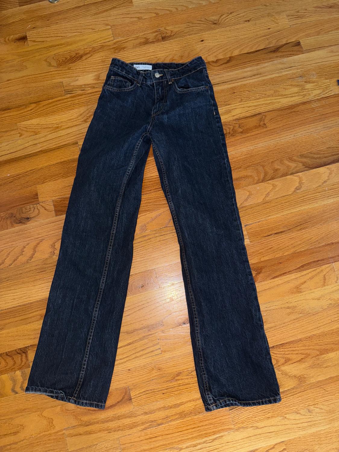 Dark, straight-leg jeans on a light wood floor.