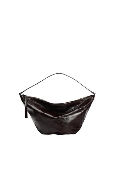 Dark brown shoulder bag with a glossy finish, crescent design, thin strap and zip fastening, on a white background.
