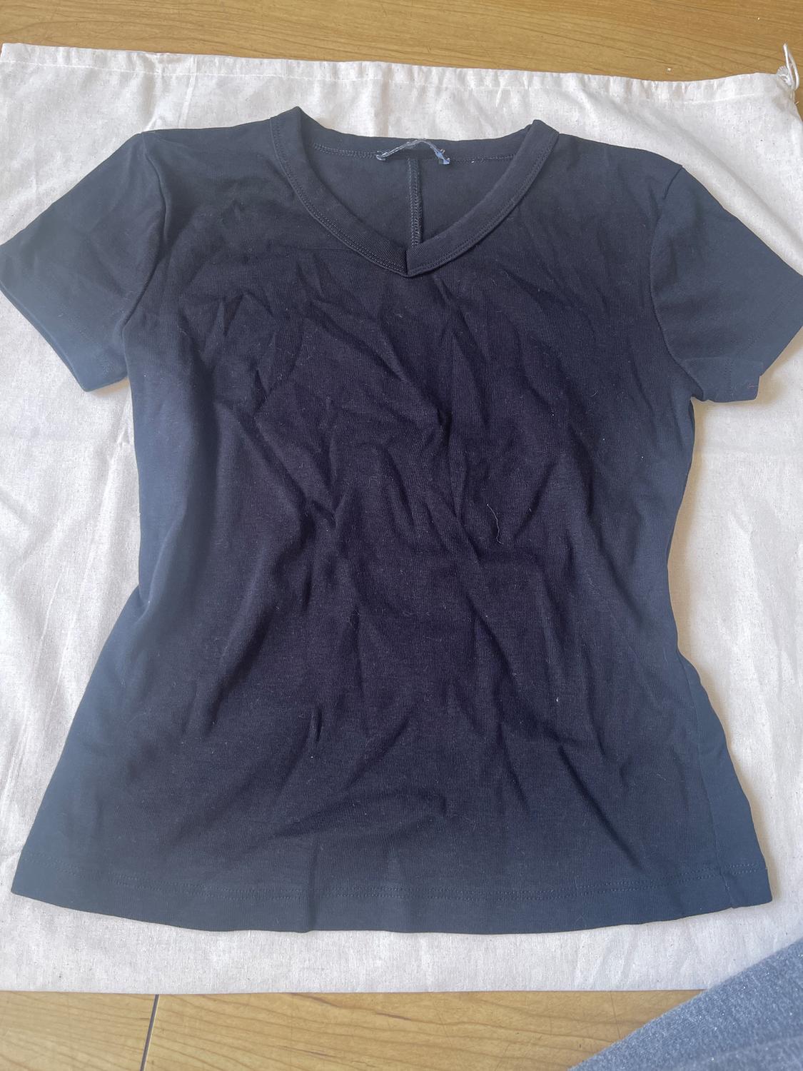 Black short-sleeved V-neck t-shirt on a white fabric, showing a simple and casual design.