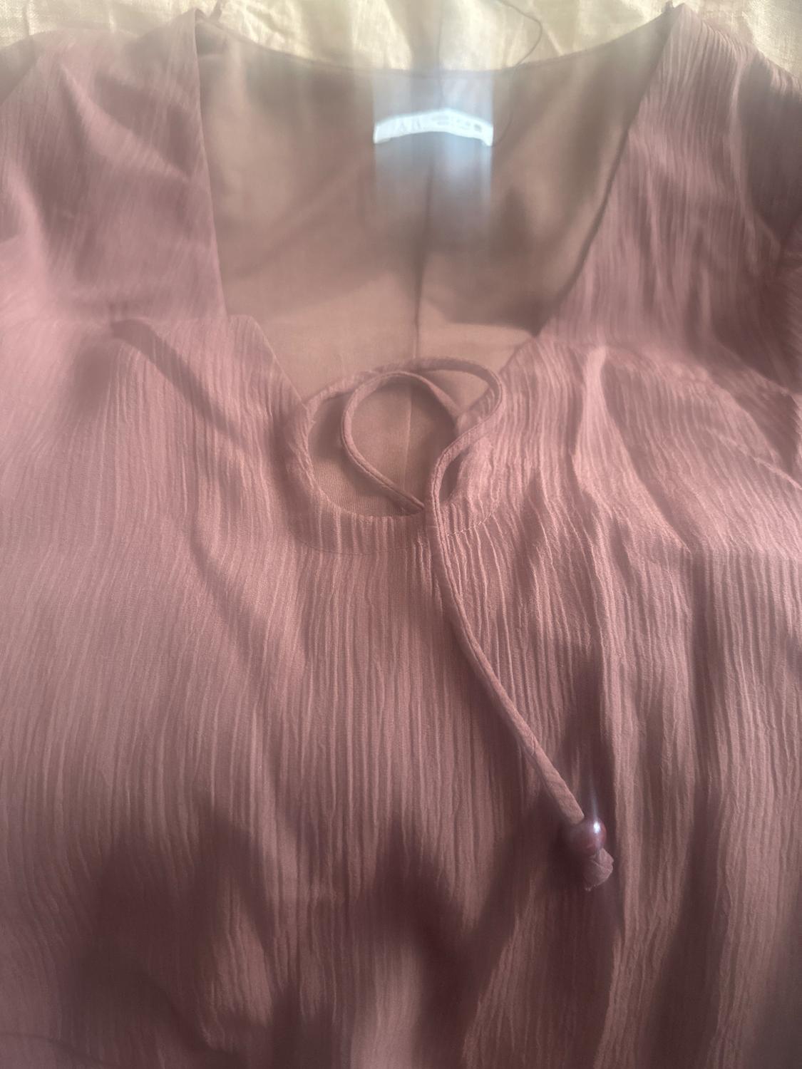 Brown crinkle-fabric blouse with a V-neckline and decorative drawstring. Light background and white label inside the collar.